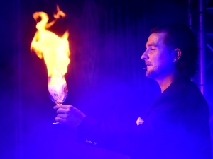 Thorsten Strotmann in phosporisierendes Scheinwerferlicht mit einer Flamme in der Hand.